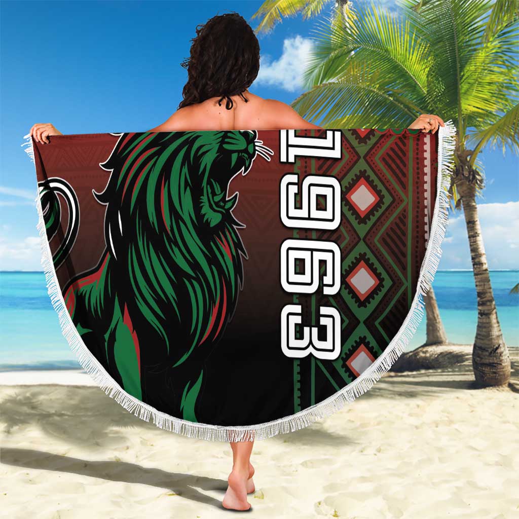 Round red Kenya beach blanket with green lion graphic and white fringe, held on beach