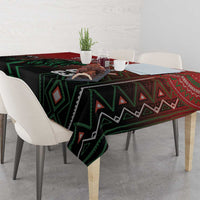 Red and black tablecloth with green patterned bands and geometric motifs, draped on table