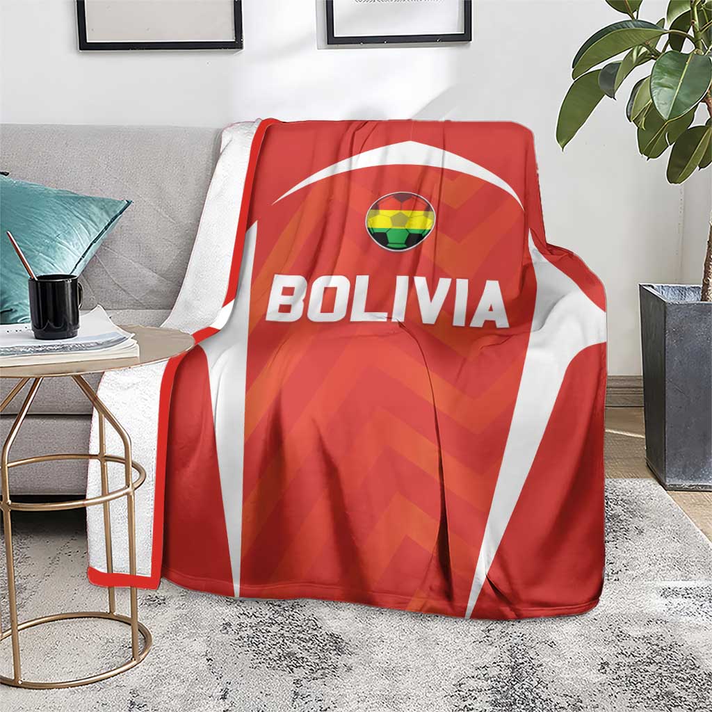 Red Bolivia football blanket with crest and BOLIVIA text, laid over grey armchair