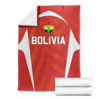 Red Bolivia football blanket with white stripes, crest and BOLIVIA text, folded with towels