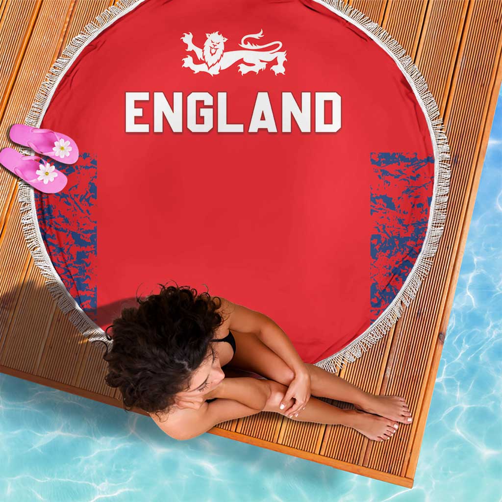 Red round England beach blanket with white fringe, “ENGLAND” lettering and blue patterned sides.