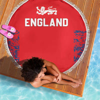 Red round England beach blanket with white fringe, “ENGLAND” lettering and blue patterned sides.