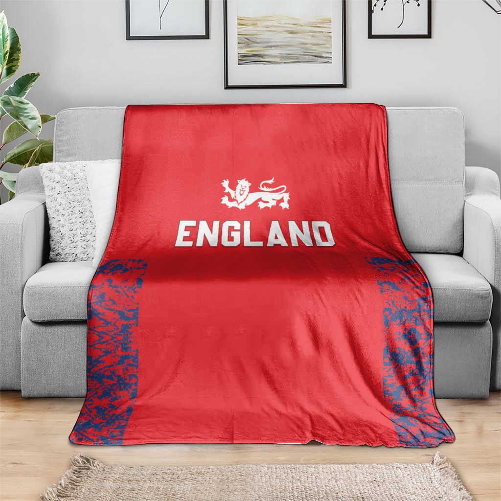 Red England cricket blanket folded over sofa, Three Lions emblem with blue edge