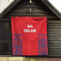 Red England quilt hanging indoors with quilted diamond stitching and blue splatter borders.