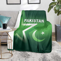 Green Pakistan cricket blanket on a living room chair with Pakistan text and crescent star