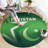 Green round Pakistan rug with 'PAKISTAN' text, star and crescent; person stepping