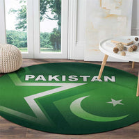 Green round Pakistan rug with 'PAKISTAN' banner, star and crescent, on wooden floor