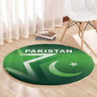 Green round Pakistan rug with 'PAKISTAN' text, star and crescent, on light wood flooring