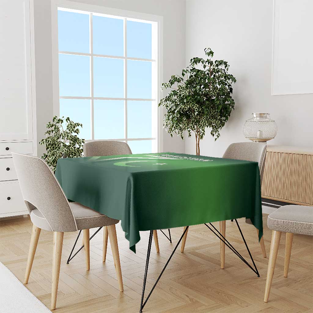 Green Pakistan-themed tablecloth covering a dining table with chairs around it.
