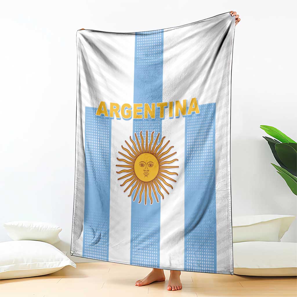 Argentina football blanket draped over bed, blue-and-white stripes with sun emblem