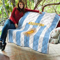 Quilt blanket with white and light-blue stripes, Argentina text and sun emblem.