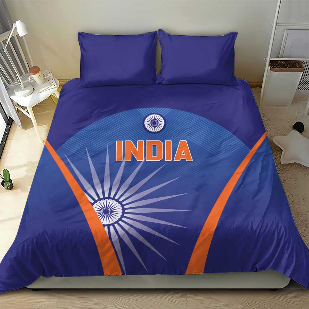Blue duvet cover with India text and sunburst motif, orange diagonal accents, two pillows