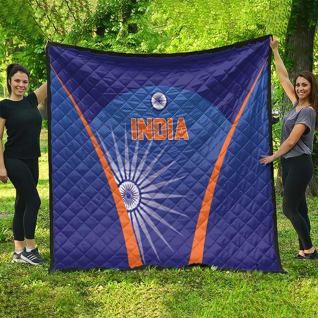 Blue India quilt draped outdoors with orange V border, 'INDIA' text and wheel graphic