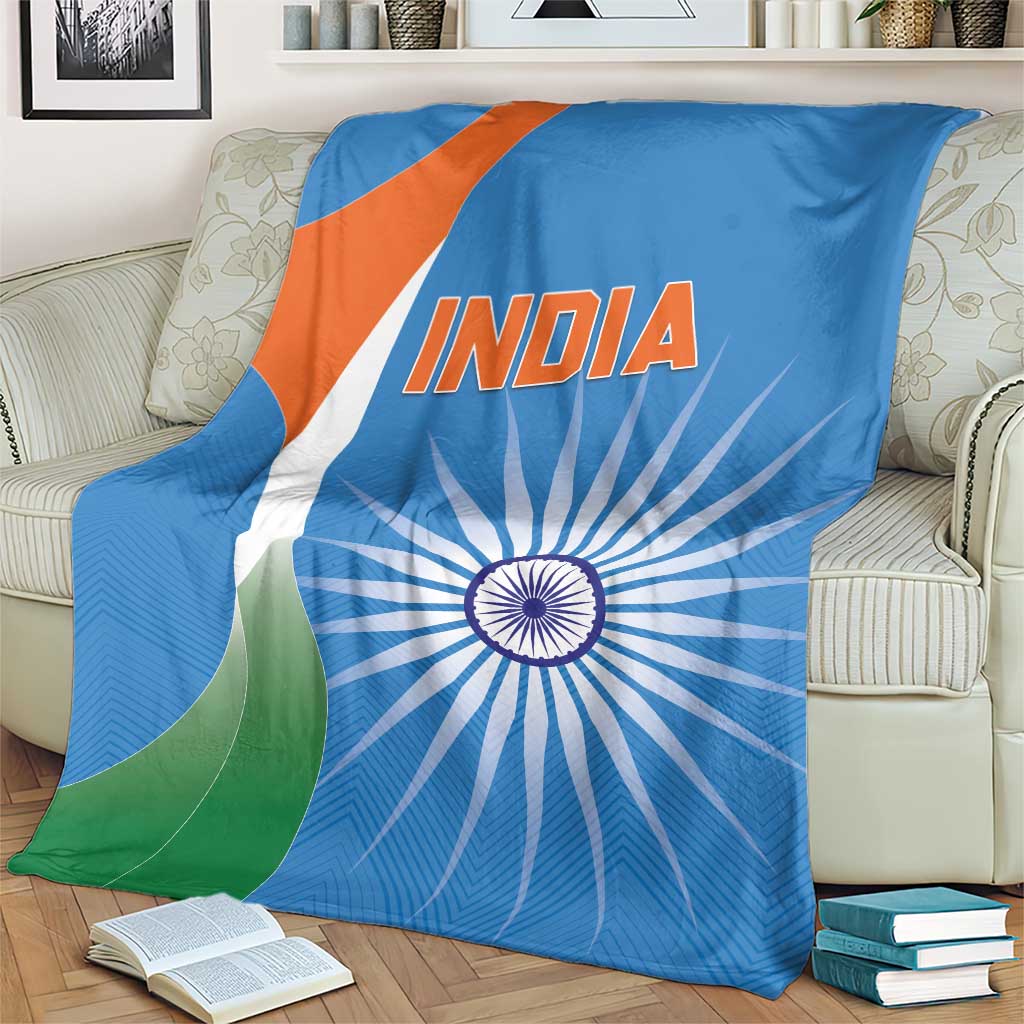 Blue India cricket blanket on couch with INDIA text, chakra circle, and green-orange diagonal shapes