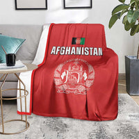 Red Afghanistan flag cricket blanket with “AFGHANISTAN” crest, on grey couch and rug
