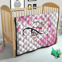 Pink floral quilt on crib, diamond quilting, stylized woman face graphic, black border trim