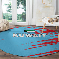 Round blue rug with red pattern and KUWAIT logo, lying flat on wooden floor