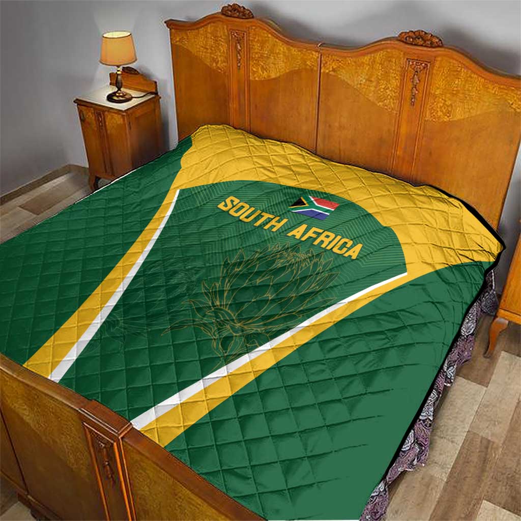 Green and yellow South Africa quilt on bed with triangle crest and 'SOUTH AFRICA' text