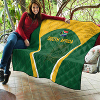 Green and yellow South Africa quilt draped over seating, triangle crest with 'SOUTH AFRICA'