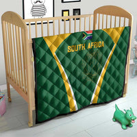 Green and yellow South Africa quilt in front of a crib with triangle crest and 'SOUTH AFRICA' text