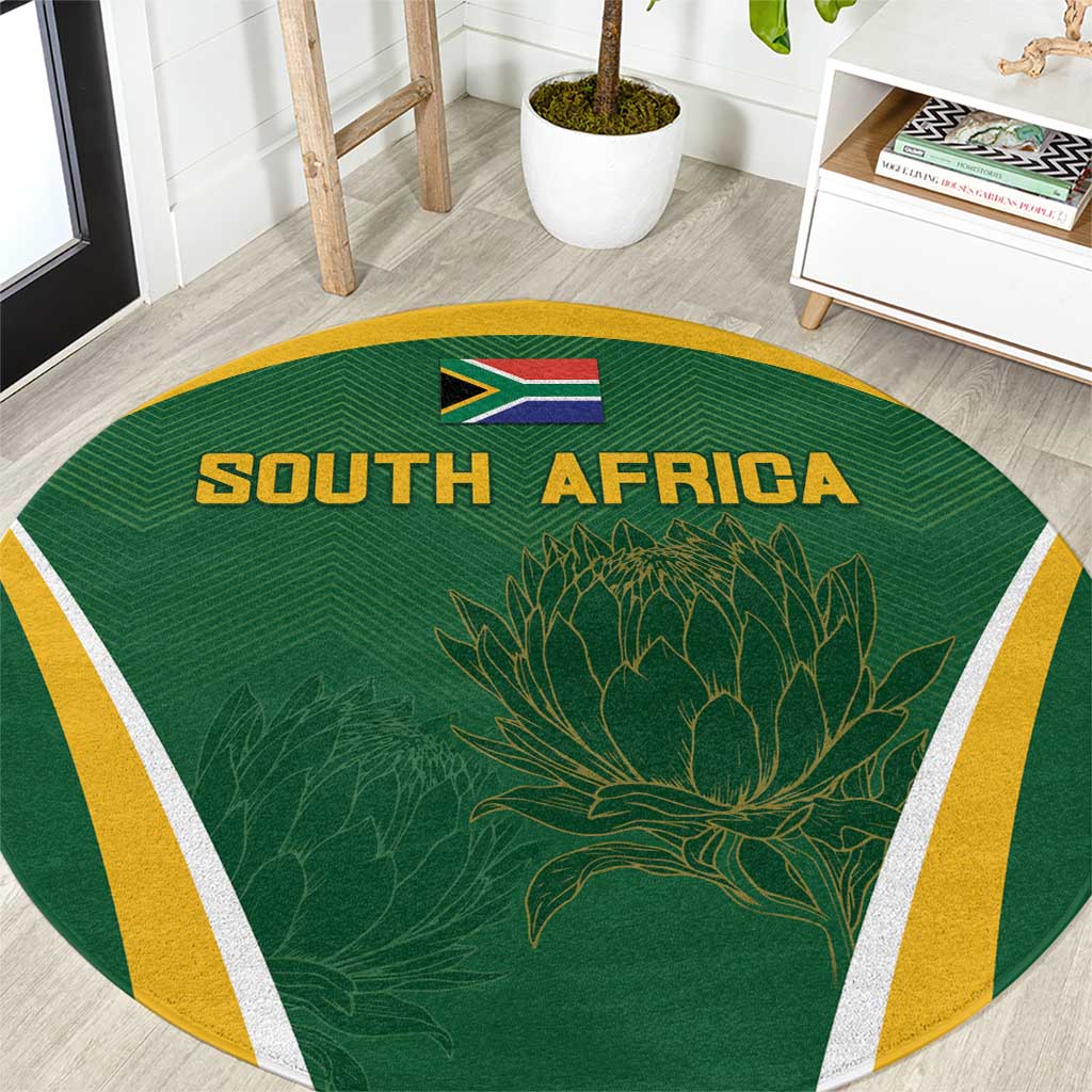 Green round carpet with SOUTH AFRICA text, South Africa flag, protea graphic, yellow border