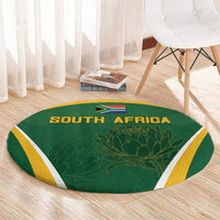 Green round carpet with SOUTH AFRICA lettering, flag and protea design, yellow border on floor