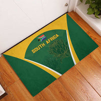 Green and yellow triangular-border rubber doormat with South Africa cricket logo and protea.