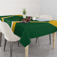 Green tablecloth draped over table with yellow trim and central emblem and protea graphic