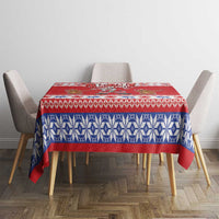 Red and blue patterned holiday tablecloth on a dining table with four chairs