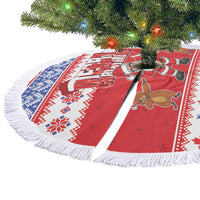 Red round Christmas tree skirt with white fringe, blue/red pattern and Santa cartoon graphics