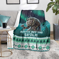 Green Christmas blanket on floor with Gryla artwork, “Watch out for Gryla” text, and pine border