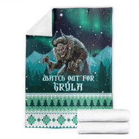 Green Christmas blanket folded with Gryla graphic, night stars, trees, and snowflake hem