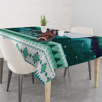 Green and teal patterned tablecloth draped over dining table with white chairs