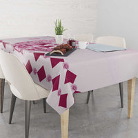 Pink and white diamond-pattern tablecloth with rose accents, folded over table edge