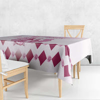Pink and white diamond-pattern tablecloth draped over table corner with rose accents