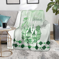 Green and white blanket draped over chair with Kentucky Derby emblem, horses, and rose detail.