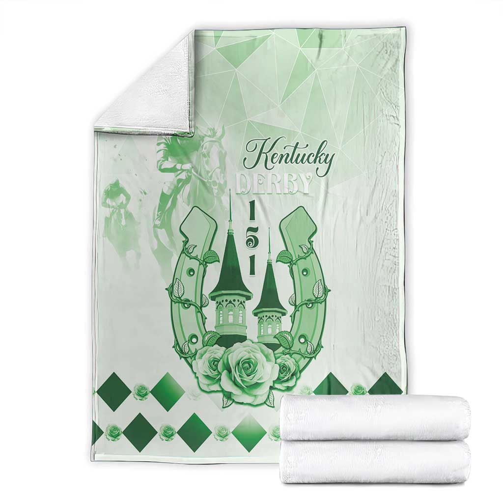 Green and white blanket with Kentucky Derby emblem, horses, roses, shown with two folded white towels.