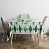 Green diamond-pattern tablecloth with central crest on round dining table