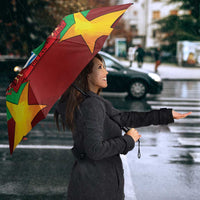 Tilted open umbrella with red, green, and yellow star shapes and central crest