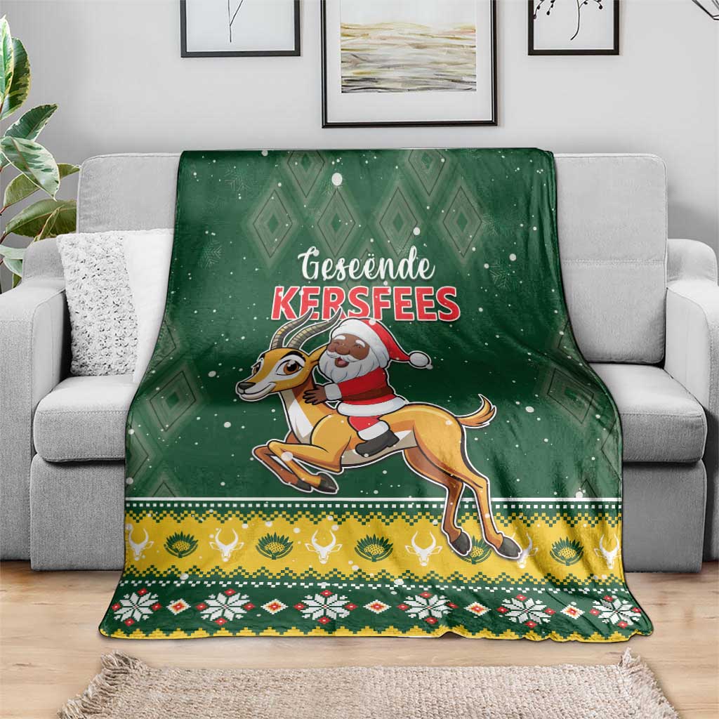 Green Christmas blanket draped on gray sofa, Santa riding springbok with patterned trim
