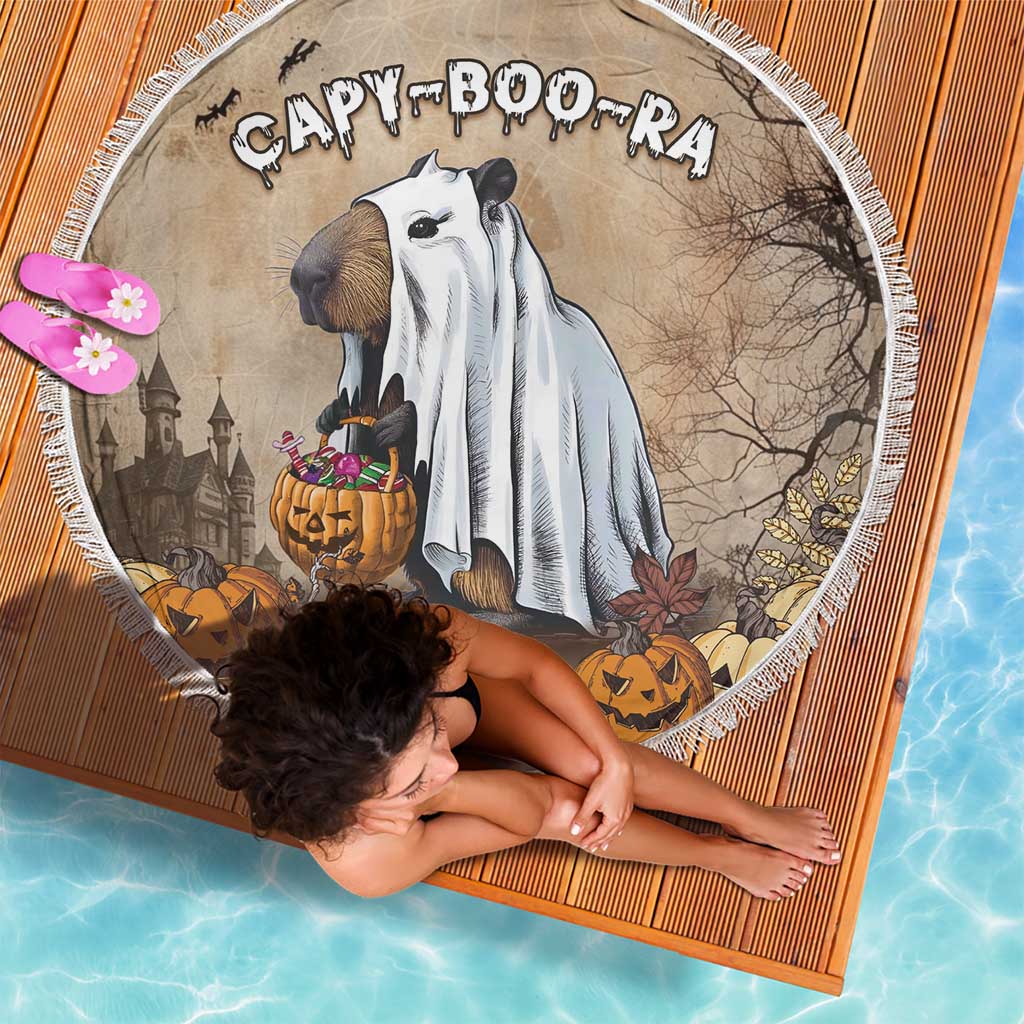 Round Halloween beach blanket with fringe edge featuring CAPY BOO-RA capybara, jack-o'-lanterns
