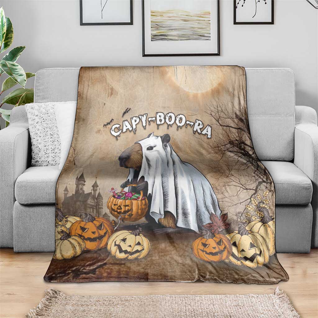 Halloween throw blanket with capybara ghost and pumpkins, laid over a gray sofa