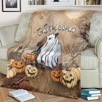 Beige Halloween blanket with capybara ghost and jack-o'-lantern pumpkins, on couch