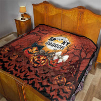Orange and black Halloween quilt on a bed, featuring jack-o-lantern, bats, and spooky season