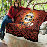 Halloween quilt draped over sofa with orange moon graphic, pumpkins, bats, and spooky season
