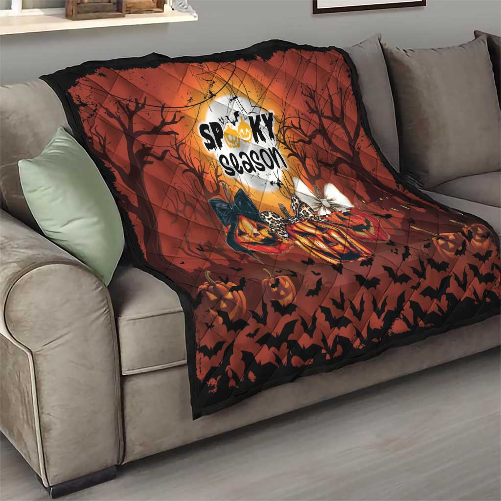 Orange-and-black Halloween throw quilt on a couch with pumpkins, bats, and spooky season logo