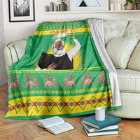 Green Christmas blanket with saint figure and festive border patterns, draped on a couch