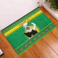 Green rubber doormat with Santa-style figure, textured grid background, bordered pattern