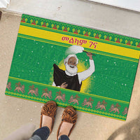 Green rubber Christmas doormat with Santa-style figure, seen with shoes on top