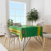 Green Christmas tablecloth draped over dining table with patterned edge and motifs